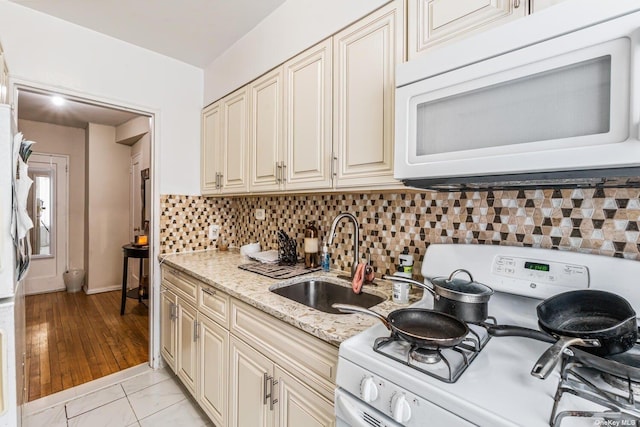 kitchen with white appliances, a sink, cream cabinets, and decorative backsplash