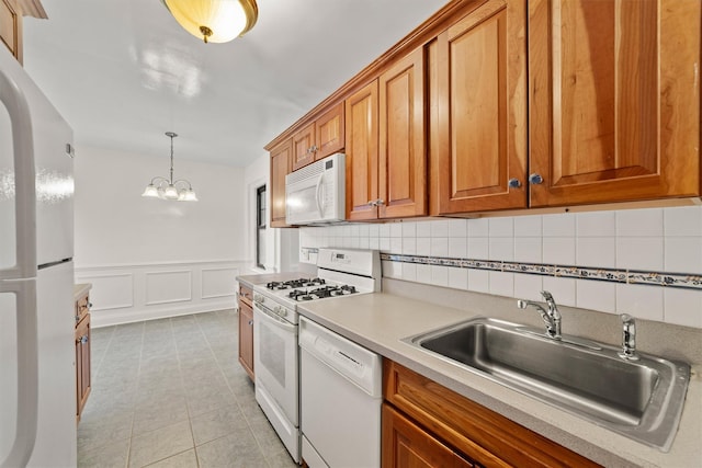 kitchen featuring white appliances, a sink, brown cabinetry, tasteful backsplash, and light countertops