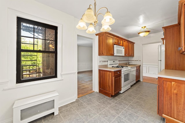 kitchen with white appliances, a chandelier, light countertops, light tile patterned flooring, and a decorative wall