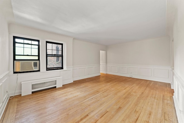 unfurnished room featuring hardwood / wood-style flooring, a decorative wall, a wainscoted wall, and cooling unit