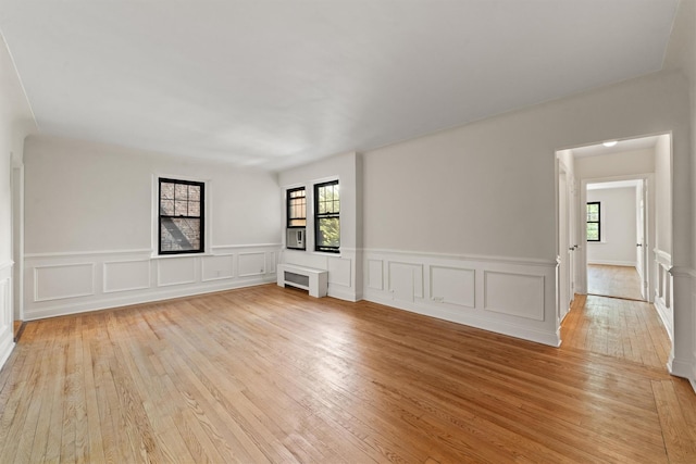 unfurnished room featuring light wood finished floors, a wainscoted wall, and a decorative wall