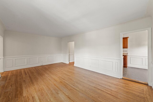 bonus room with a wainscoted wall, light wood-style floors, and a decorative wall