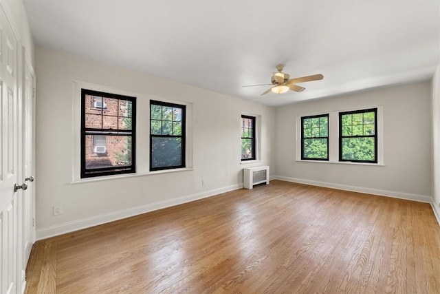 spare room featuring healthy amount of natural light, light wood-style flooring, ceiling fan, and baseboards
