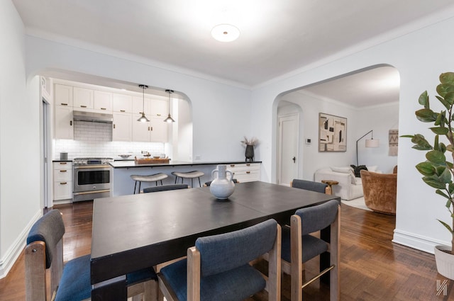 35-06 88th St Unit 5E, Jackson Heights, NY 11372 - dining room featuring arched walkways, crown molding, baseboards, and dark wood-style flooring