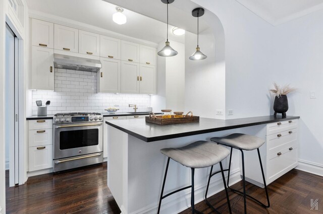 35-06 88th St Unit 5E, Jackson Heights, NY 11372 - kitchen with stainless steel gas range, range hood, dark countertops, white cabinets, and a kitchen breakfast bar