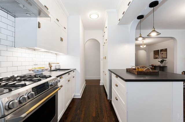 35-06 88th St Unit 5E, Jackson Heights, NY 11372 - kitchen featuring stainless steel gas stove, dark countertops, under cabinet range hood, arched walkways, and decorative backsplash
