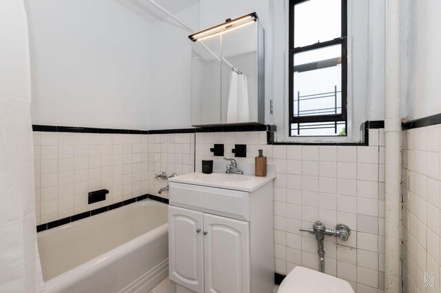 35-06 88th St Unit 5E, Jackson Heights, NY 11372 - bathroom with tile walls, a tub to relax in, vanity, a wainscoted wall, and toilet