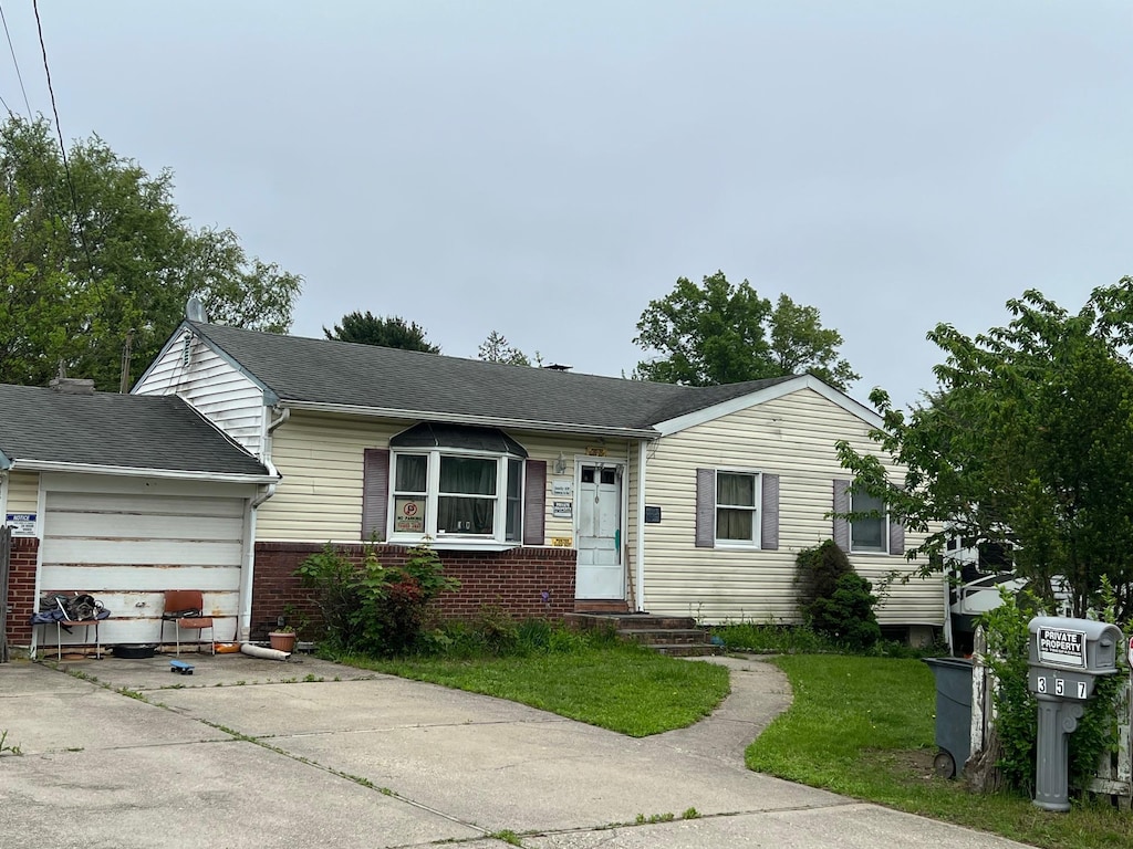 21 Pinetop Dr, Central Islip, NY 11722 - view of front of property with concrete driveway, a garage, brick siding, and a front yard