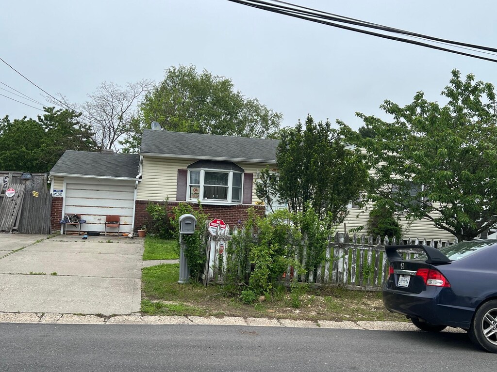 21 Pinetop Dr, Central Islip, NY 11722 - view of front of home with brick siding, driveway, fence, and a garage