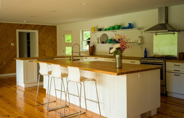 35 Jilroy Ln, Spencertown, NY 12165 - kitchen with butcher block counters, wall chimney exhaust hood, gas range, light wood finished floors, and wood walls