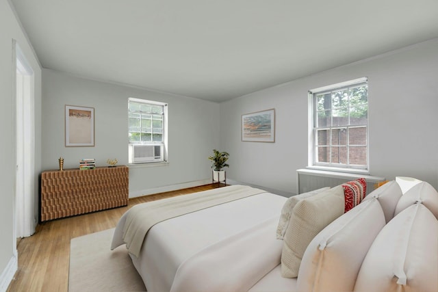 bedroom with multiple windows, light wood-type flooring, and cooling unit