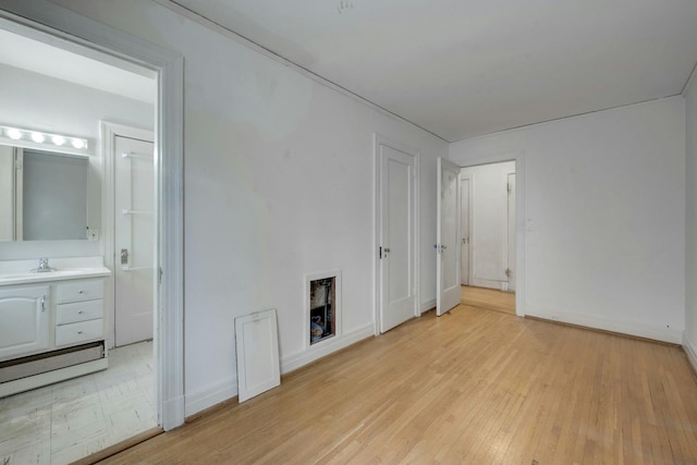 unfurnished living room with a sink, light wood-type flooring, and baseboards