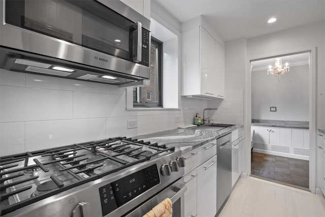 100 E Hartsdale Ave Unit Tfw, Hartsdale, NY 10530 - kitchen with appliances with stainless steel finishes, a sink, white cabinets, light stone counters, and a chandelier