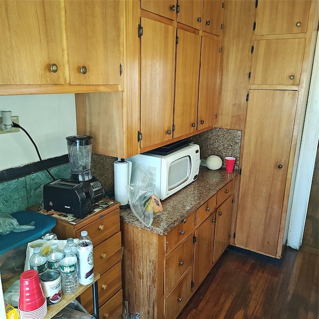 27 Coolidge Ave, Amityville, NY 11701 - kitchen featuring dark wood-style flooring, white microwave, brown cabinetry, and dark stone counters