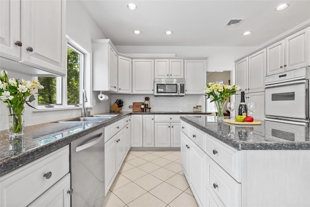 47 Londonderry Ln, Somers, NY 10589 - kitchen featuring stainless steel appliances, a sink, tasteful backsplash, light tile patterned flooring, and white cabinetry