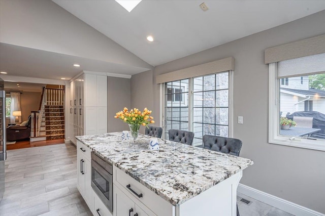 11 Fishermans Dr, Port Washington, NY 11050 - kitchen featuring stainless steel microwave, light stone counters, white cabinetry, recessed lighting, and lofted ceiling