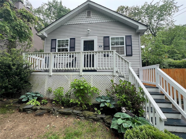 view of front facade with a deck, stairs, and fence