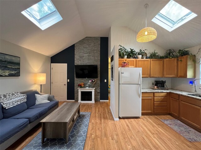 kitchen featuring freestanding refrigerator, a skylight, open floor plan, a sink, and high vaulted ceiling