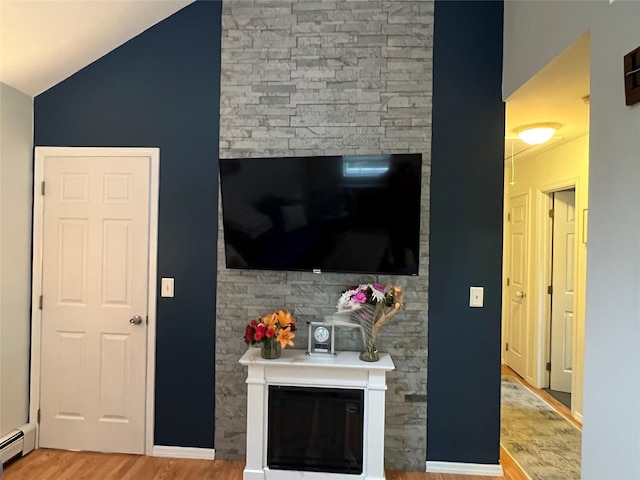 living room with wood finished floors, a glass covered fireplace, a baseboard radiator, and lofted ceiling