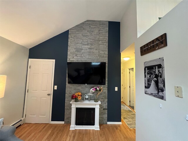 living room featuring light wood-style flooring, baseboard heating, a glass covered fireplace, and high vaulted ceiling