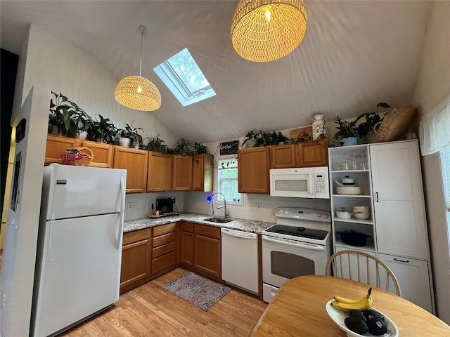 kitchen with white appliances, a sink, a skylight, vaulted ceiling, and light wood-style flooring