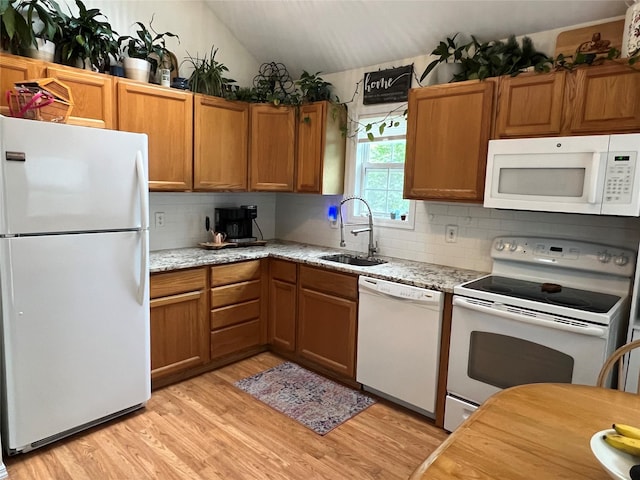 kitchen with white appliances, a sink, backsplash, light wood-style floors, and vaulted ceiling