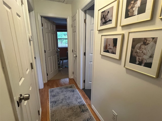 hall featuring dark wood-type flooring and baseboards