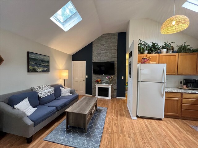 living room featuring a skylight, light wood finished floors, a large fireplace, and high vaulted ceiling