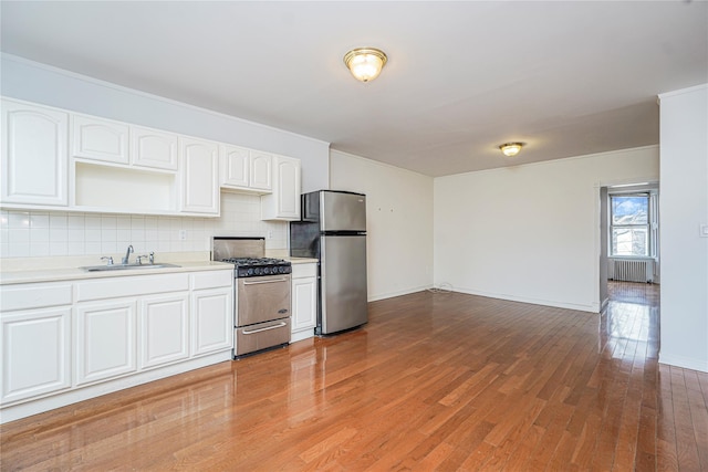 146 Nelson St, Brooklyn, NY 11231 - kitchen featuring appliances with stainless steel finishes, a sink, radiator, light wood-style flooring, and backsplash