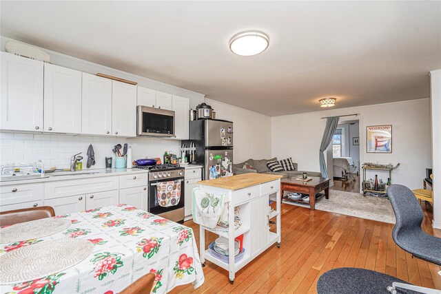 146 Nelson St, Brooklyn, NY 11231 - kitchen featuring appliances with stainless steel finishes, a sink, white cabinetry, light wood finished floors, and tasteful backsplash
