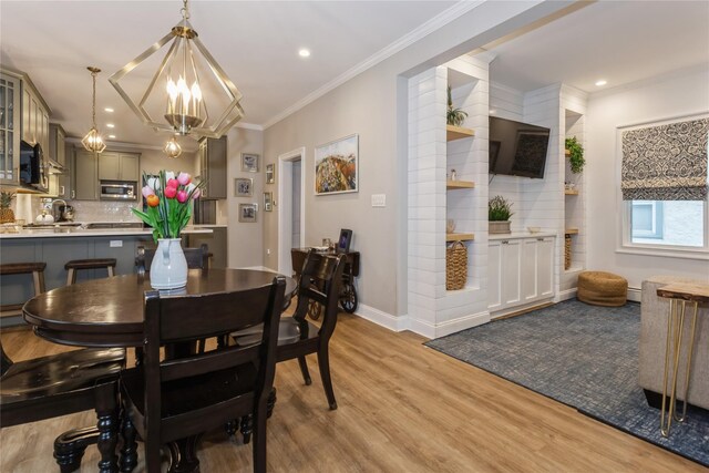 dining space with a chandelier, light wood-style floors, ornamental molding, baseboards, and recessed lighting