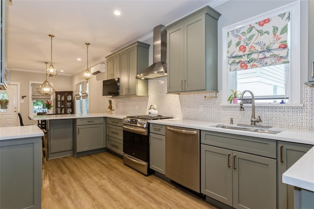 kitchen featuring wall chimney range hood, stainless steel appliances, gray cabinetry, an AC wall unit, and a sink
