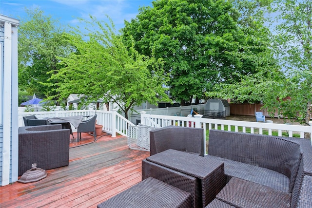 deck with outdoor dining area, a shed, an outdoor structure, and a fenced backyard