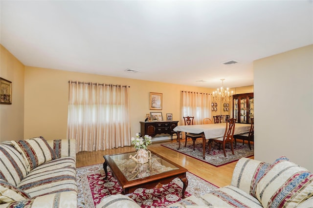 living room with a chandelier, wood finished floors, and healthy amount of natural light