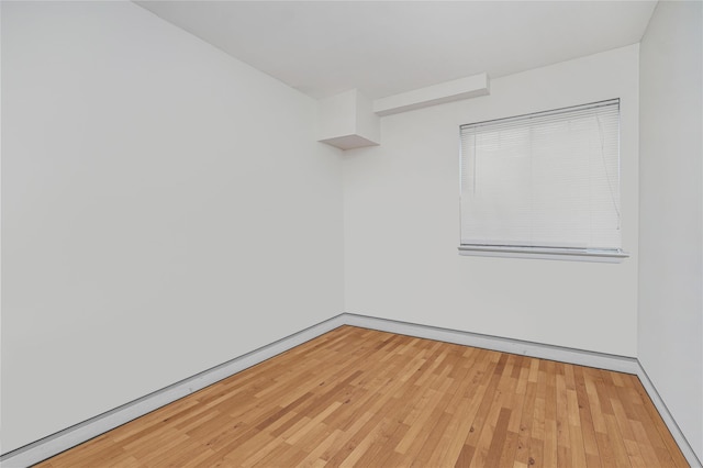 spare room featuring light wood-style floors and baseboards