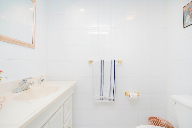 bathroom with tile walls, toilet, and vanity