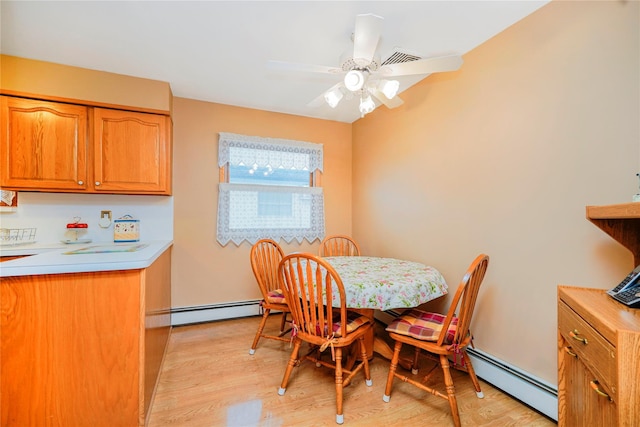 dining room featuring baseboard heating, light wood finished floors, and a ceiling fan