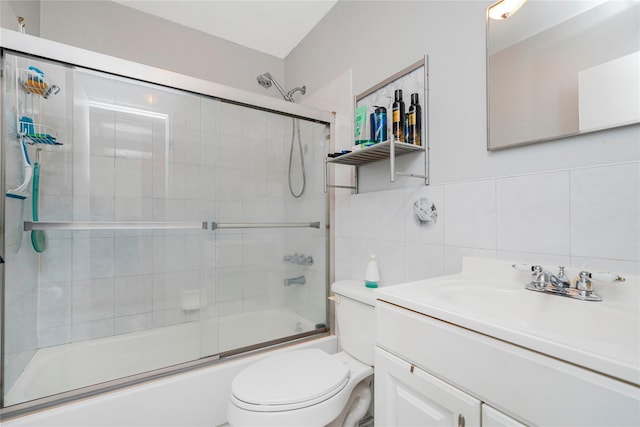 bathroom with enclosed tub / shower combo, toilet, vanity, tile walls, and tasteful backsplash