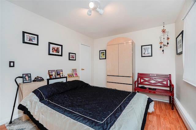 bedroom featuring light wood-type flooring, arched walkways, and baseboards