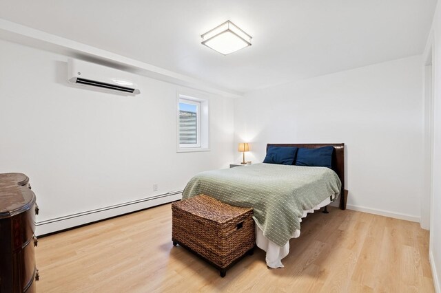 40 Grafton St, Greenlawn, NY 11740 - bedroom featuring a baseboard radiator, an AC wall unit, wood finished floors, and baseboards
