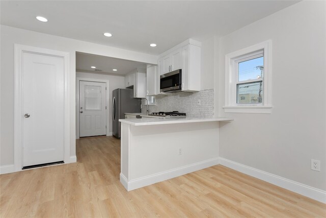 208 W Alhambra Ave, Lindenhurst, NY 11757 - kitchen featuring stainless steel appliances, light countertops, white cabinets, light wood-type flooring, and a peninsula