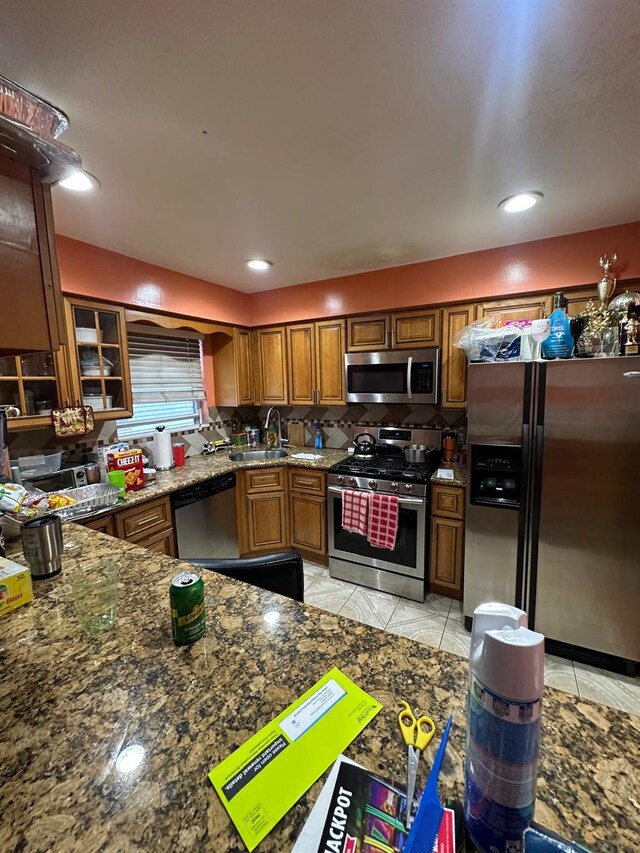 14207 135th Ave, Jamaica, NY 11436 - kitchen with stainless steel appliances, light tile patterned flooring, a sink, brown cabinetry, and decorative backsplash