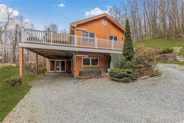 24 Babbling Brook Ln, Cold Spring, NY 10516 - view of front facade with gravel driveway, a wooden deck, a front lawn, and a carport
