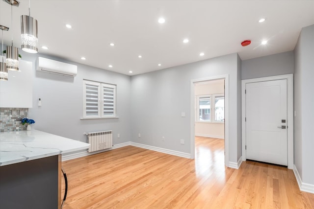 61-13 62nd St, Middle Village, NY 11379 - kitchen featuring radiator, a wall mounted AC, light wood-style floors, recessed lighting, and light stone counters
