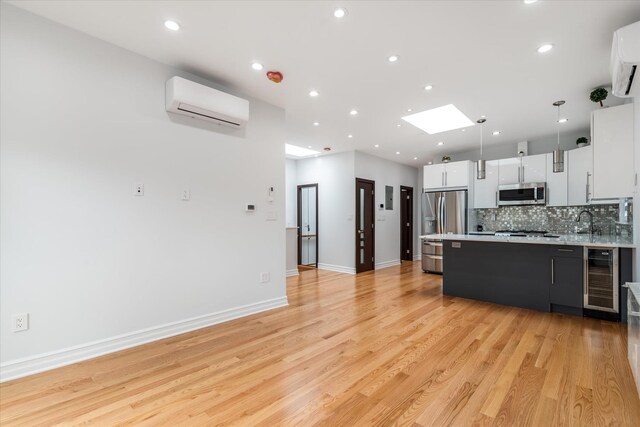 61-13 62nd St, Middle Village, NY 11379 - kitchen featuring stainless steel appliances, a wall mounted air conditioner, wine cooler, light countertops, and a peninsula
