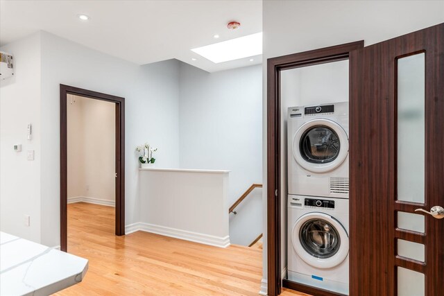 61-13 62nd St, Middle Village, NY 11379 - laundry area with stacked washer and clothes dryer, a skylight, light wood finished floors, recessed lighting, and baseboards