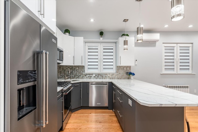 61-13 62nd St, Middle Village, NY 11379 - kitchen featuring high quality appliances, a sink, a peninsula, light wood finished floors, and tasteful backsplash