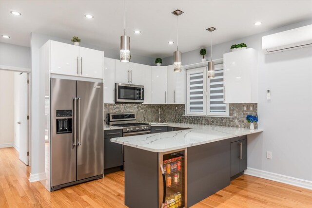 61-13 62nd St, Middle Village, NY 11379 - kitchen featuring stainless steel appliances, an AC wall unit, white cabinetry, a peninsula, and light wood finished floors
