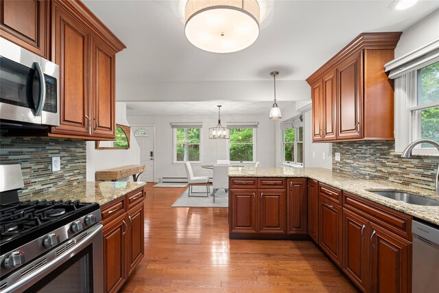 60 Hagerman Ave, East Patchogue, NY 11772 - kitchen featuring appliances with stainless steel finishes, a sink, wood finished floors, decorative backsplash, and light stone countertops