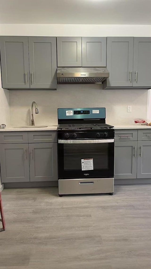 1505 E 29th St, Brooklyn, NY 11229 - kitchen featuring stainless steel gas range oven, under cabinet range hood, gray cabinetry, decorative backsplash, and light countertops